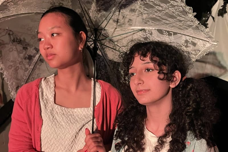 Two OVATION! senior acting students sharing a scene beneath lace parasols during the Senior Acting Production in Richmond Hill
