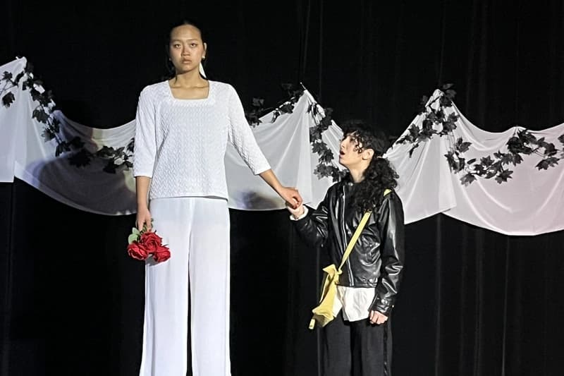 OVATION! senior actors performing a scene with red roses against a draped backdrop at the Senior Acting Production