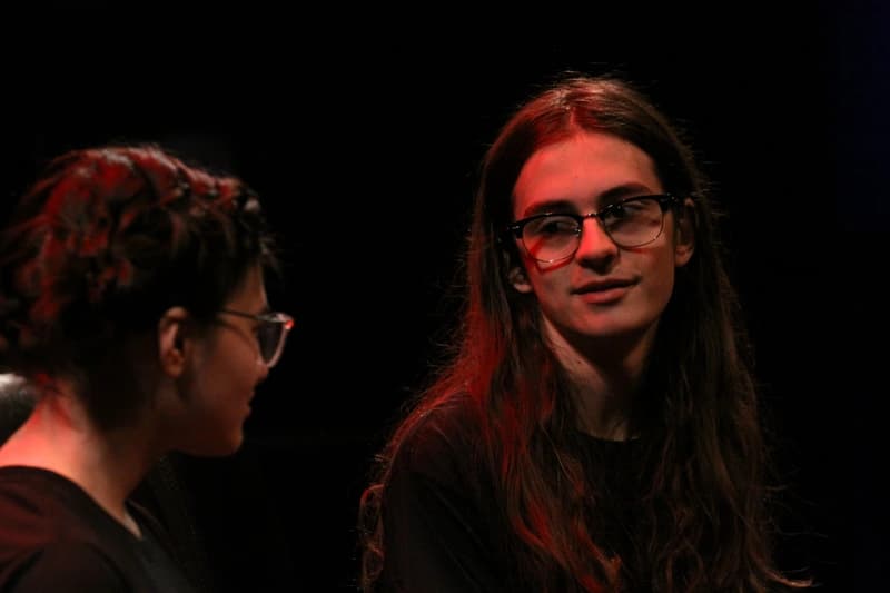 Two OVATION! senior acting students in a dimly lit dramatic scene during the Senior Acting Production