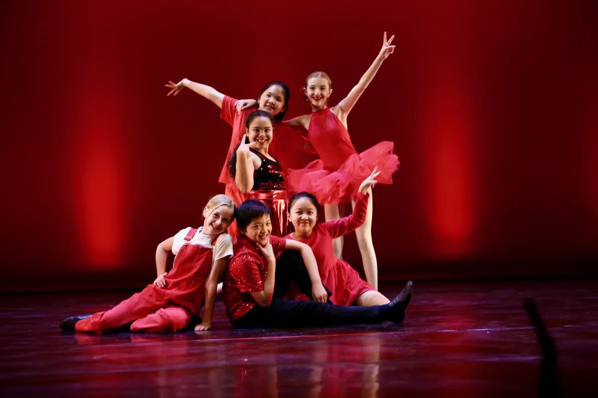 OVATION! dancers in red costumes posing in a pyramid with peace signs at the Richmond Hill studio