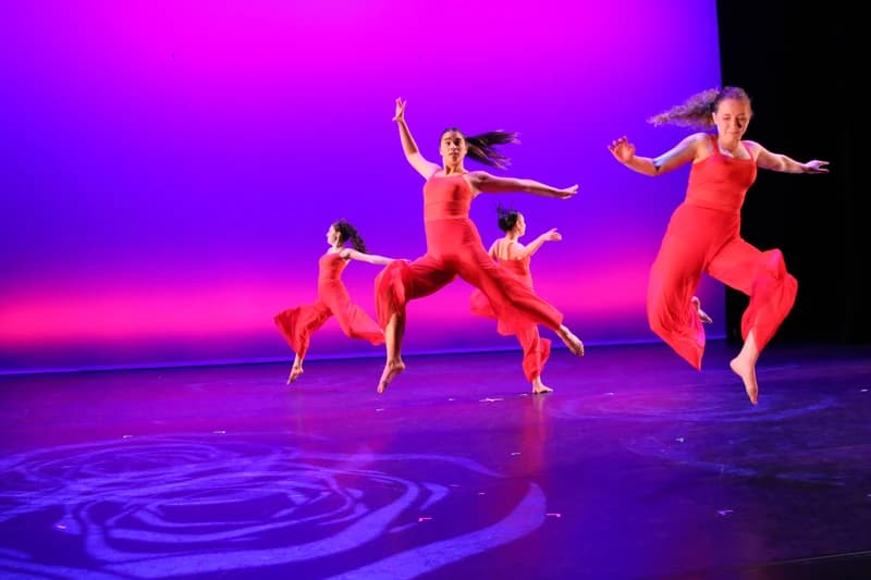 OVATION! jazz dancers in red jumpsuits leaping mid-air at a Richmond Hill showcase