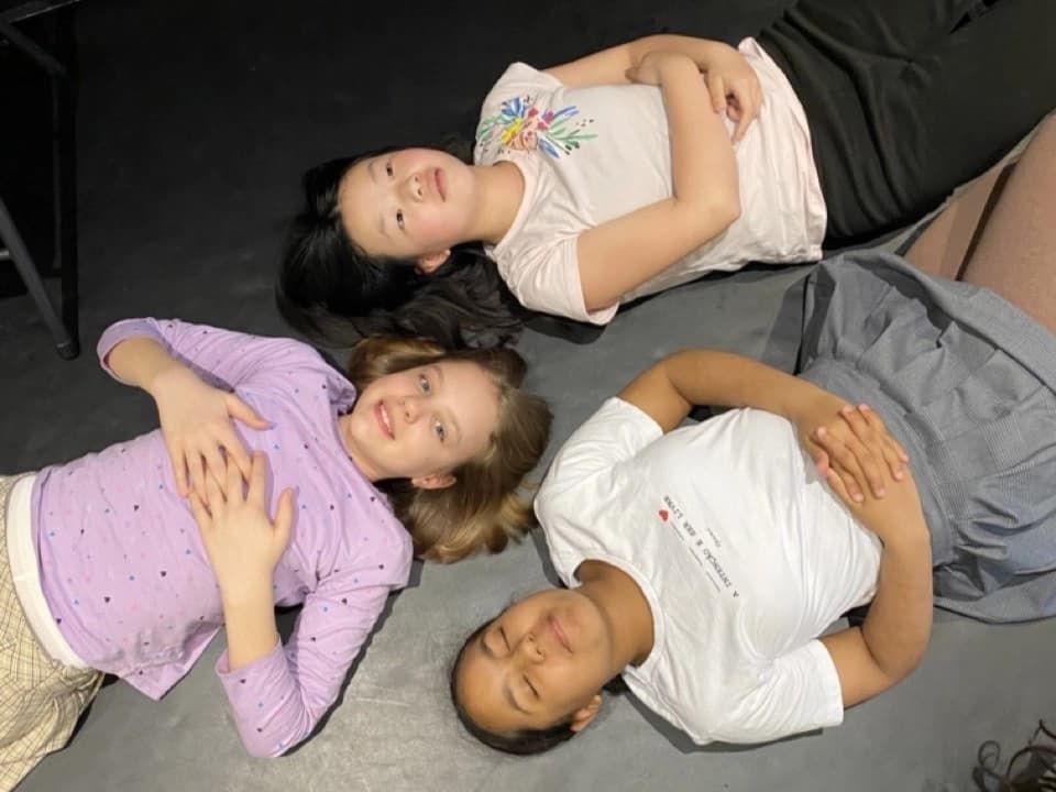 Three OVATION! summer campers lying head-to-head on the studio floor in Richmond Hill