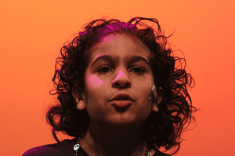OVATION! musical theatre camp performer singing on stage against an orange backdrop in Richmond Hill