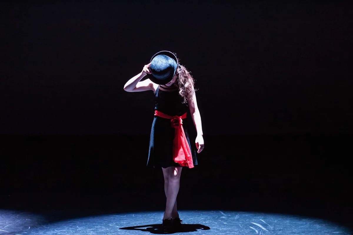 OVATION! tap dancer in a black dress and red sash tipping her hat on the Richmond Hill stage